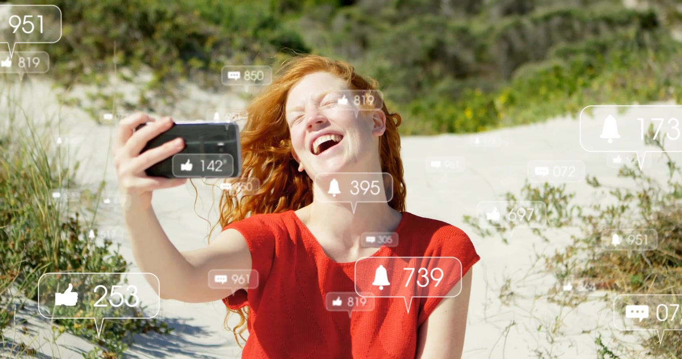Mujer levantando el smartphone en una duna, generando 'me gusta', comentarios y notificaciones animadas para redes sociales.