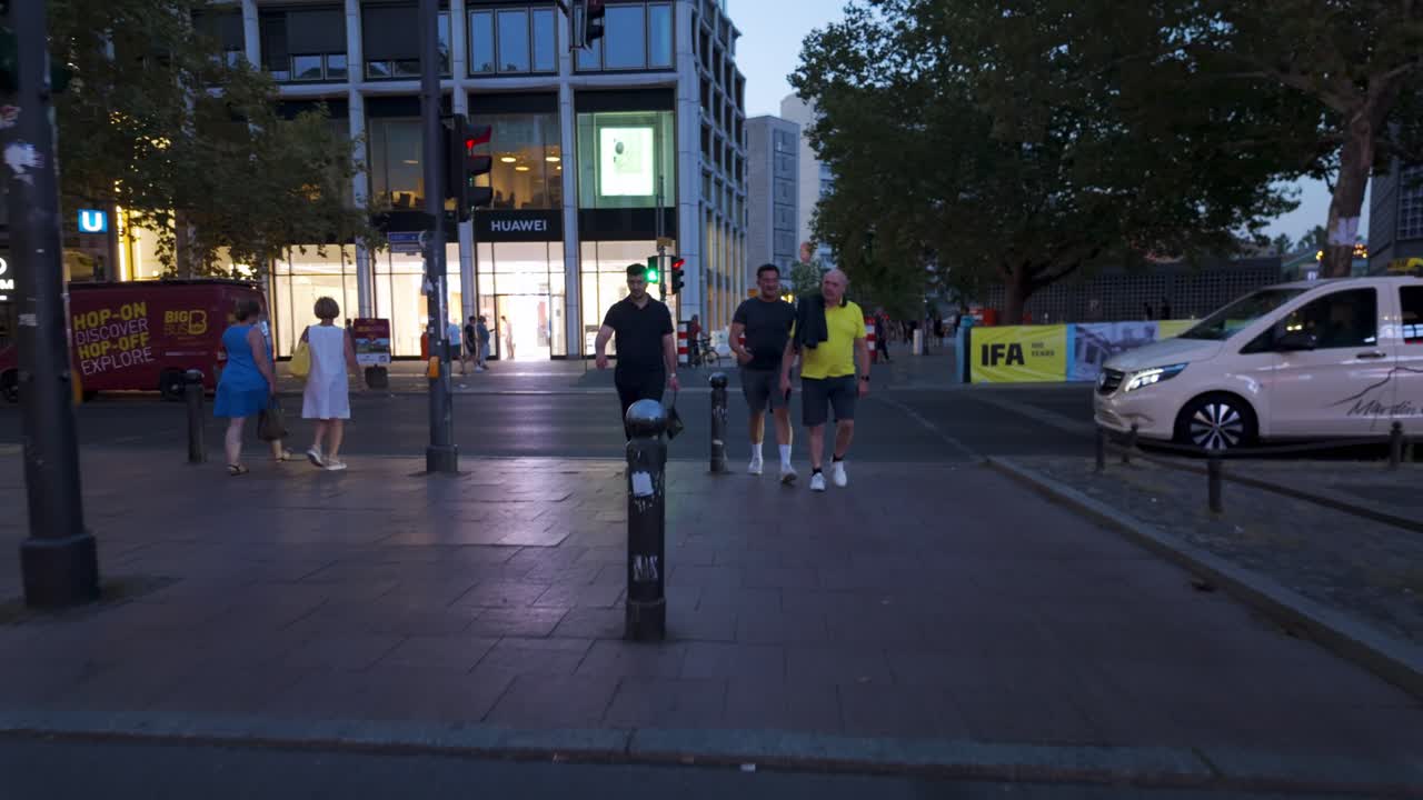 Street scene in Berlin during the IFA tech event, featuring pedestrians walking in the evening, urban life, and city transport with a dolly forward camera movement towards the Huawei store