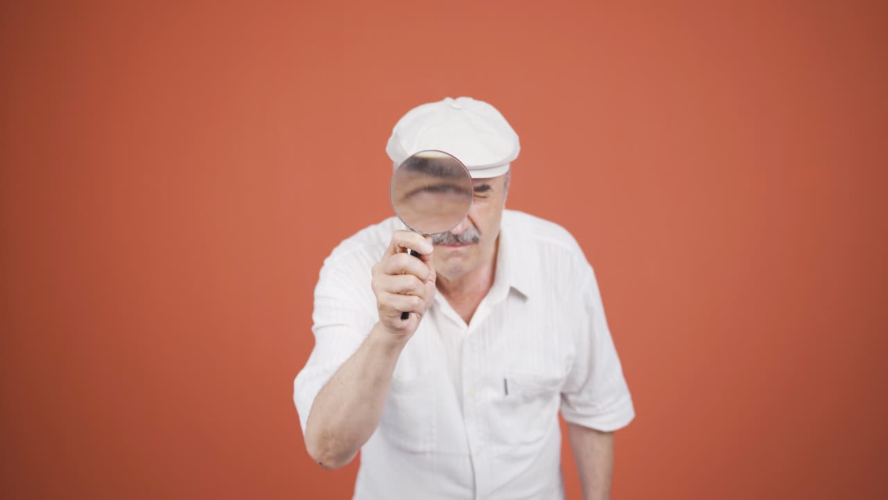 hombre viejo mirando a la cámara con lupa.