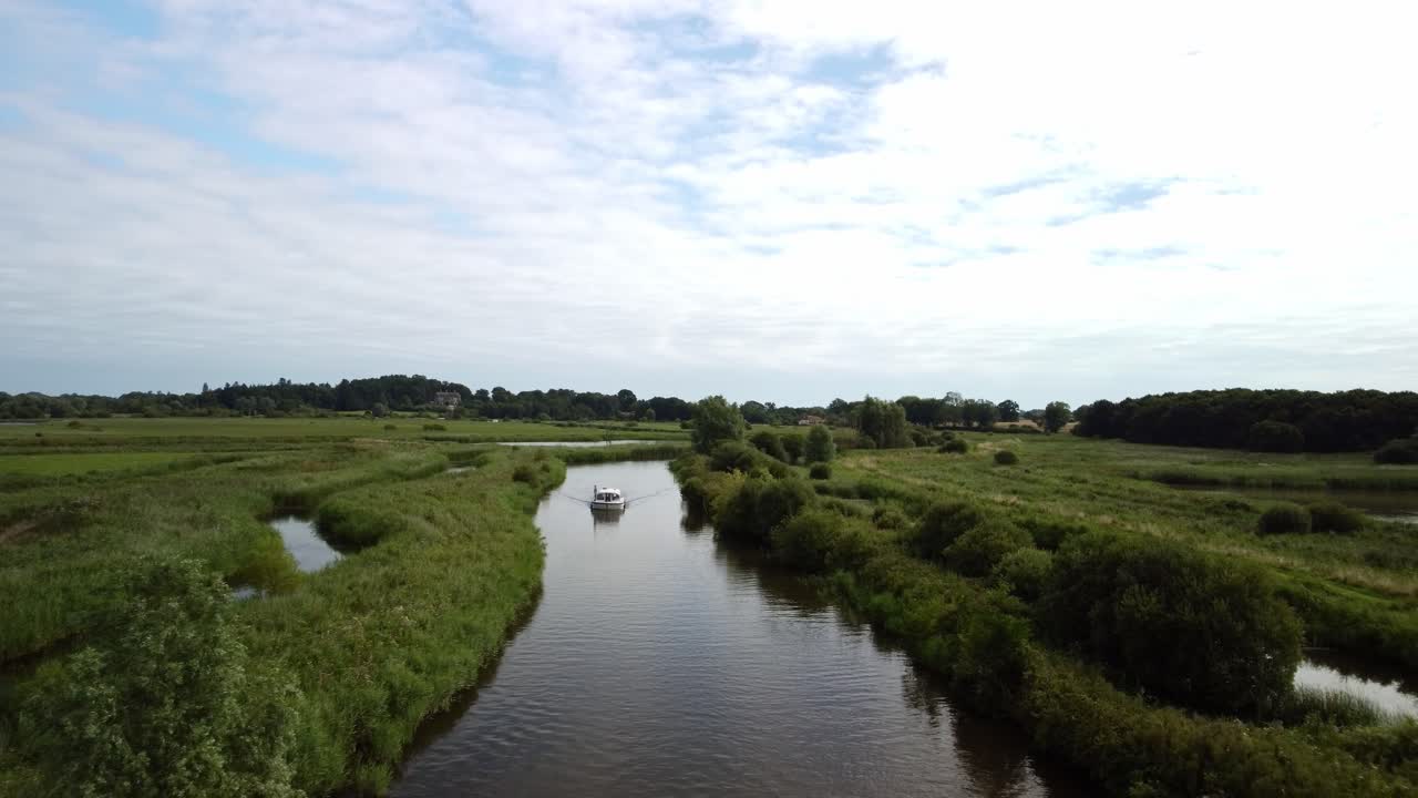 Aerial Drone Footage of a Boat travelling along still reflection of the River Yare in the Norfolk Broads