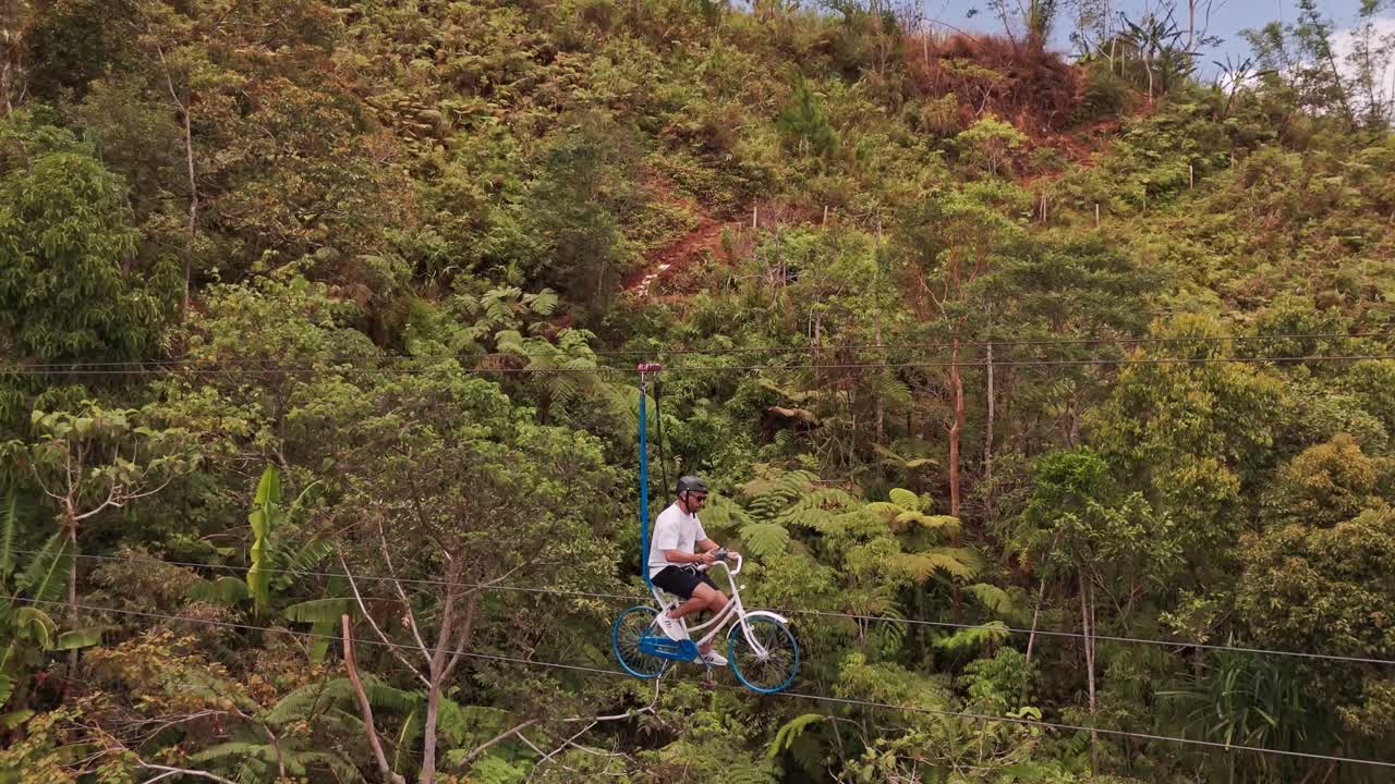Cinematic 4K aerial shot of a tourist riding a sky bike suspended on cables over a tropical jungle in the Philippines, ideal for travel, adventure, and eco-tourism projects