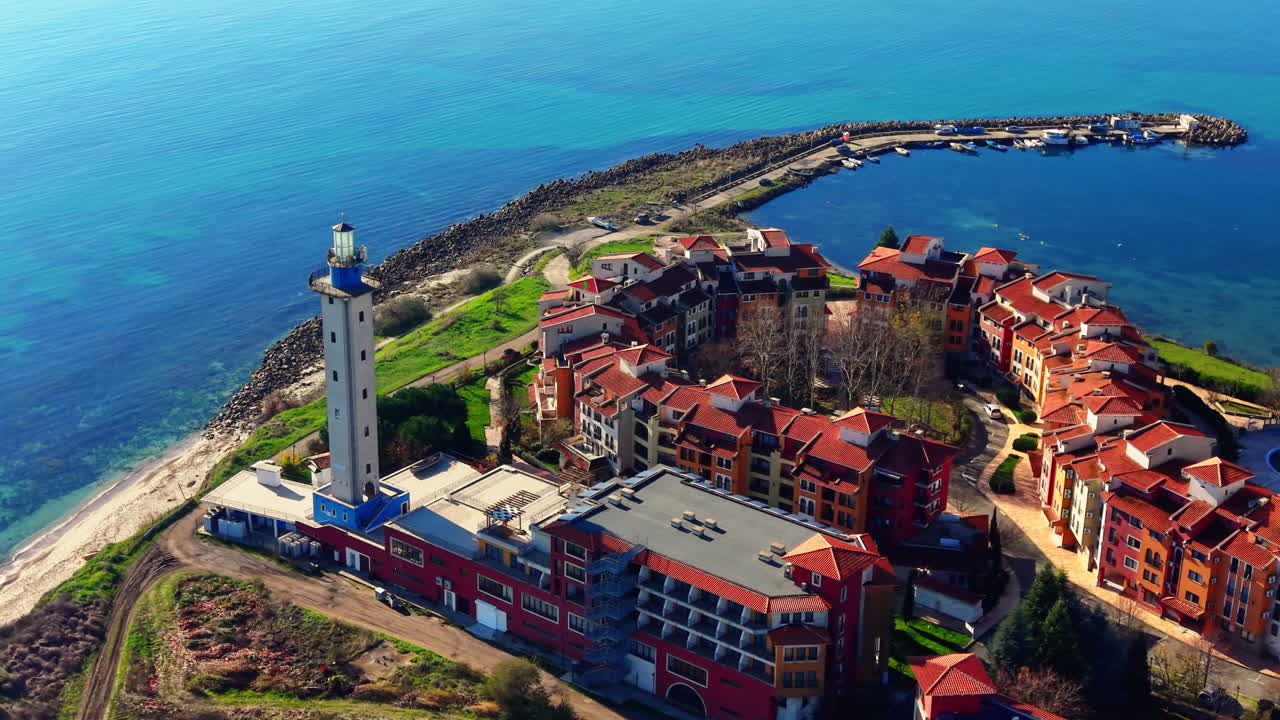 Edifici colorati, strada tortuosa e porto con barche vicino a un alto faro sulla pittoresca costa. Vista aerea del Mar Nero in Bulgaria