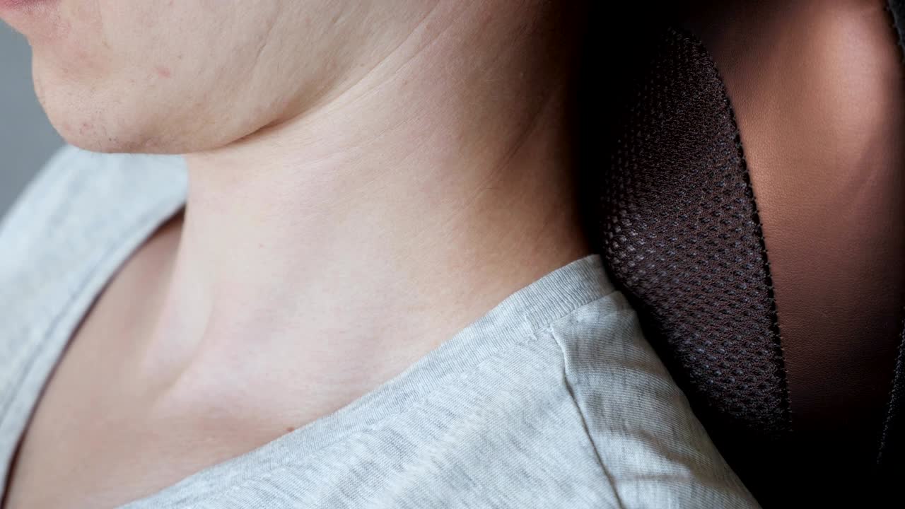 긴장을 풀어주는 마사지 베개를 가진 남자 목의 가까운 곳에서 진동하는 전기