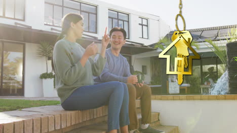 animation of gold house key and key fob over happy diverse couple by house