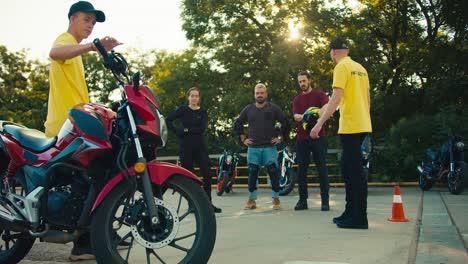 Two-instructor-guys-in-a-driving-school-communicate-with-their-students.-A-group-of-motorcyclists-stand-at-the-driving-range-along-with-motorcycles