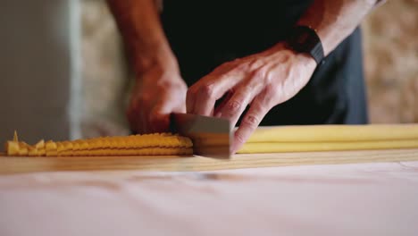 captura de cámara lenta de un chef italiano cortando un trozo de pasta hecha a mano, sobre un paño blanco con un fondo de pared de piedra