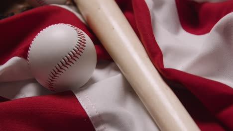 Cerrar-Bodegón-De-Béisbol-Con-Bate-Y-Pelota-En-La-Bandera-Americana-1