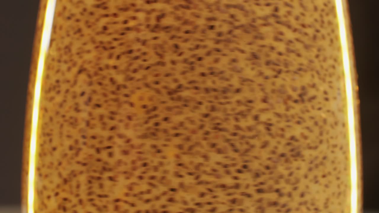 Chia seeds blending and rotating in water close-up macro yellow background. Dry healthy ingredient. Healthy superfood rich in Omega 3 fatty acids. Salvia hispanica