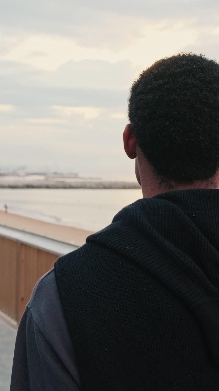 Giovane uomo che guarda il mare da una passerella