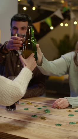 Vertical-Video-Of-Group-Of-Friends-At-Home-Or-In-Bar-Celebrating-At-St-Patrick's-Day-Party-Drinking-Alcohol-And-Doing-Cheers-Together