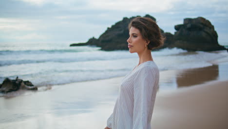 beautiful brunette walking shore on cloudy day. smiling lady enjoy summer coast