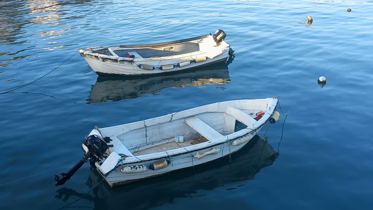 dos pequeños barcos de pesca amarrados en el muelle marítimo, con aguas tranquilas y azules