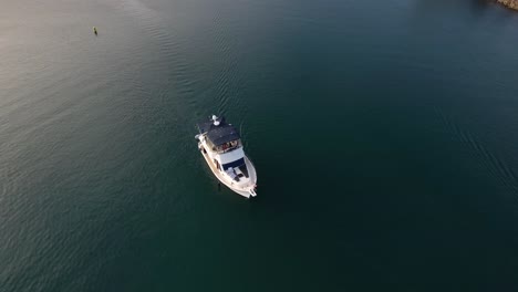 Motorboat-cruise-along-Dana-Point-Marina,-Topdown-view-following-white-vessel-in-Deep-blue-water