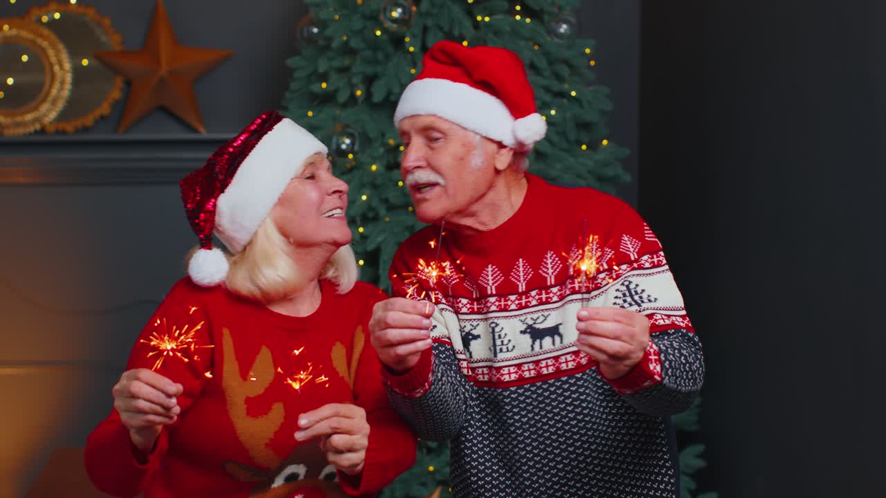 feliz pareja familiar madura con ropa festiva agitando luces de bengala en casa, víspera de navidad
