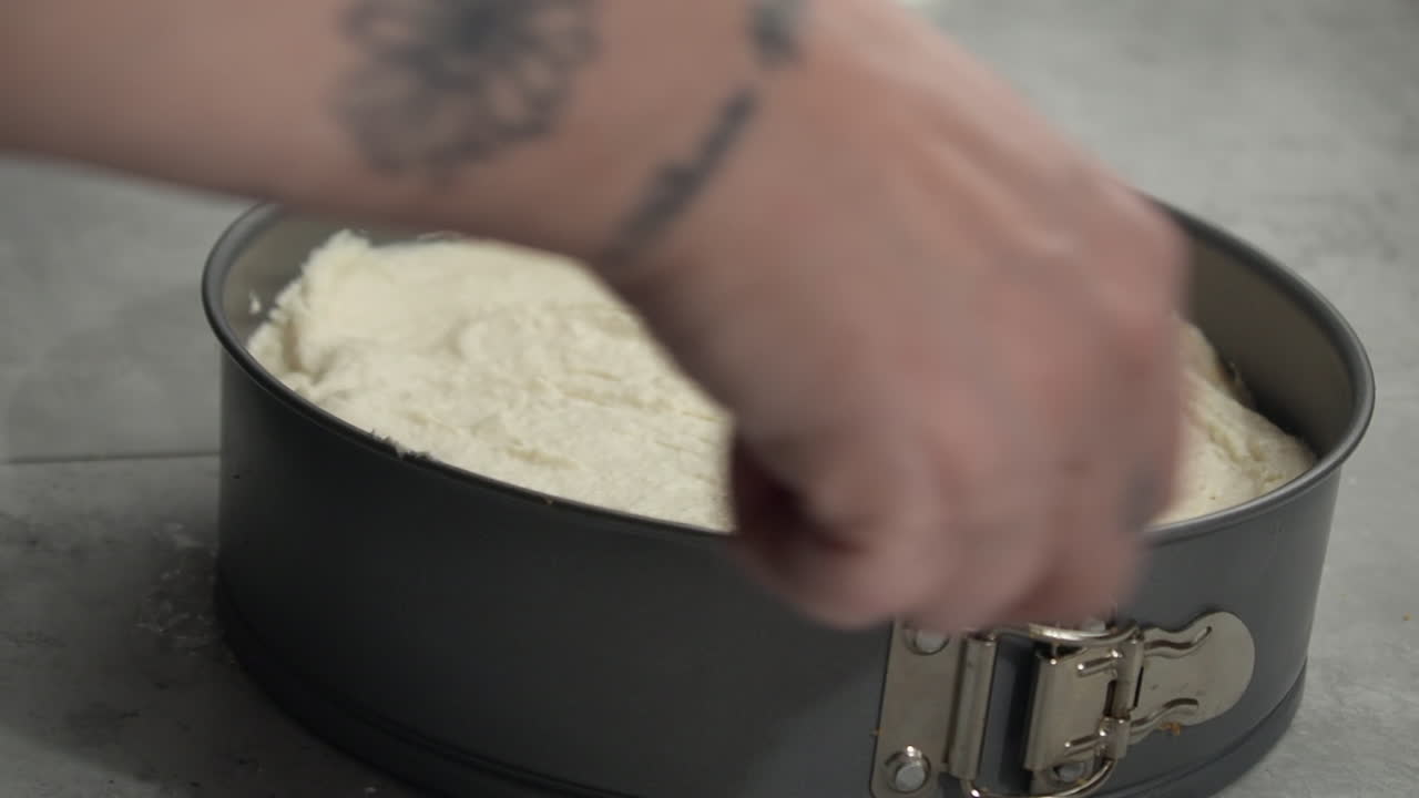 relleno de tarta de queso esparcido en molde desmontable con cuchara, mano derecha