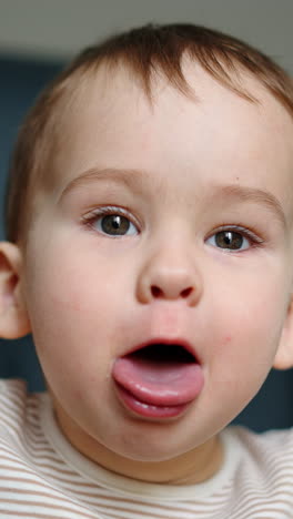 beautiful joyful kid shows tongue to camera. kid sits in black chair looking and speaking to camera. close up. vertical video
