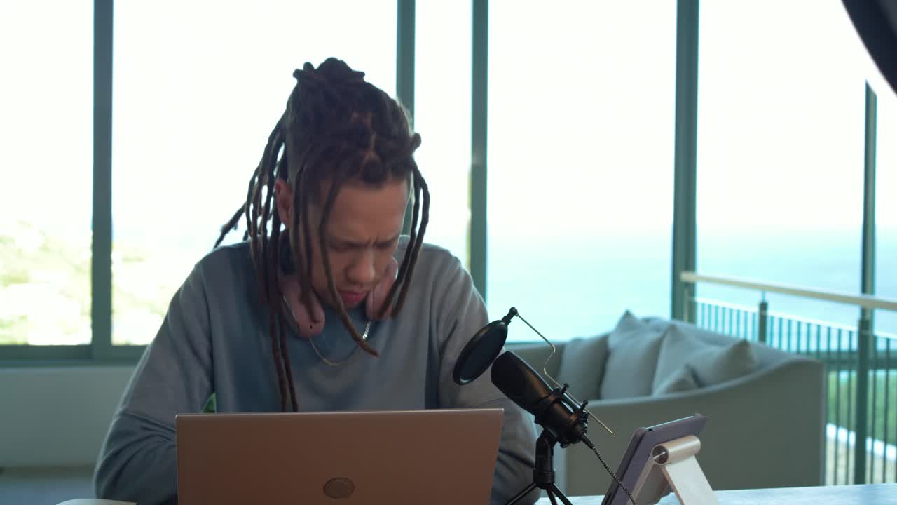 Mand justerer telefon på ring light på kontor med havudsigt, noterer og taler til podcast