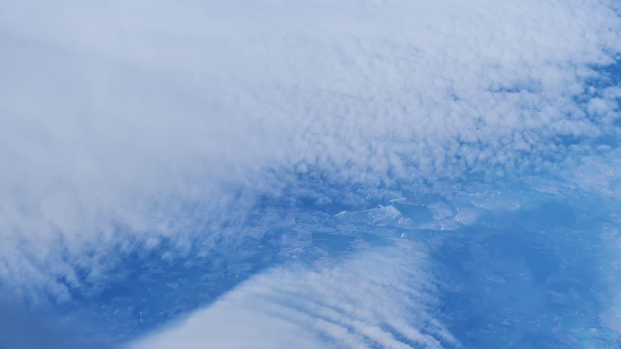 Aerial airplane window view reveals scenic clouds, land below during Europe