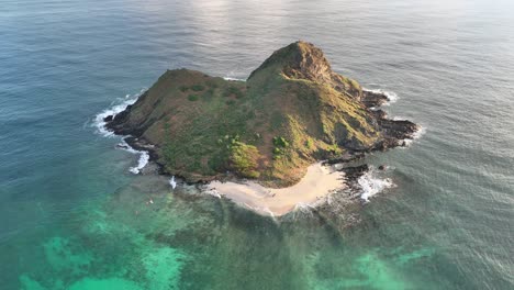 pan-out-of-mokulua-islands-in-lanikai-oahu-hawaii-zooming-out-from-beach-to-show-beautiful-clear-reefs-and-ocean-and-calm-ocean-at-sunrise-paradise