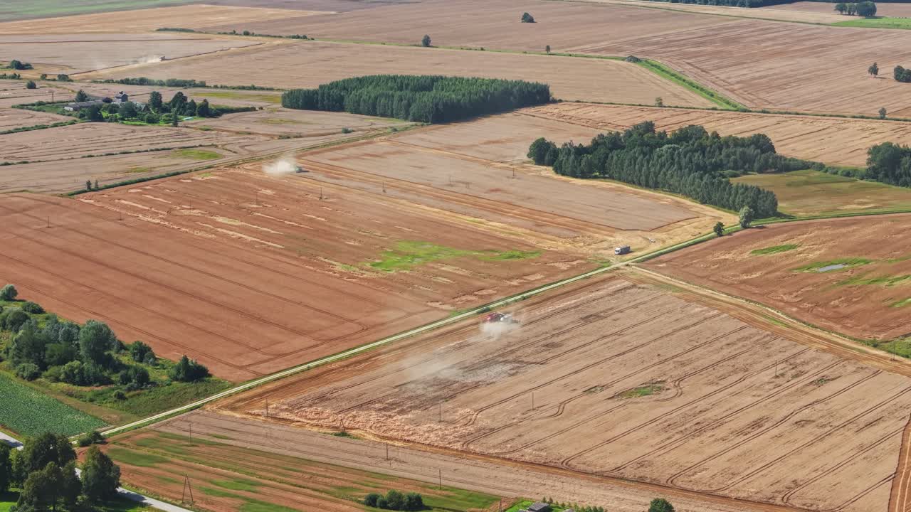 Drone overview of large combine harvesting grain fields with dry landscape around