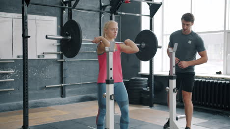 woman weightlifting with coach in gym