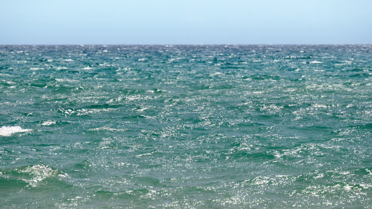 View of glittering turquoise sea surface with small wind driven waves on a sunny day