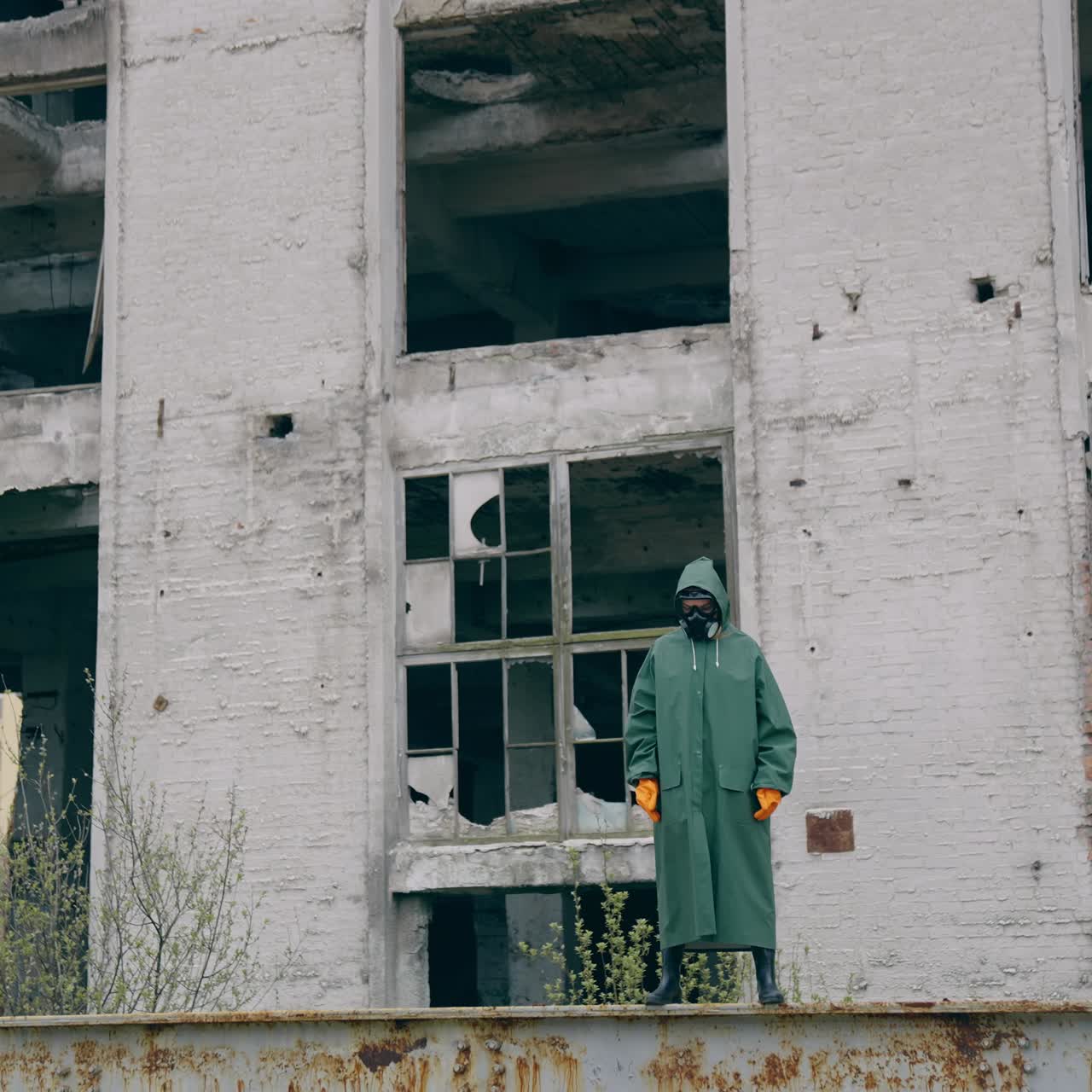 Stalker in military protective clothing. Lonely human in protective gas mask and military clothes walking on old factory