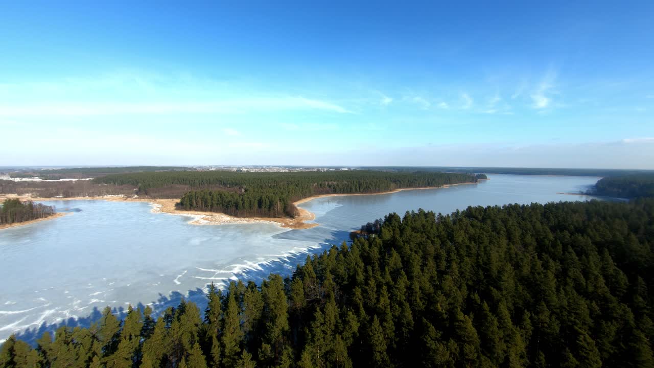 una hermosa toma aérea hacia atrás de un paisaje con un enorme lago congelado y un bosque de abetos durante el invierno, polonia