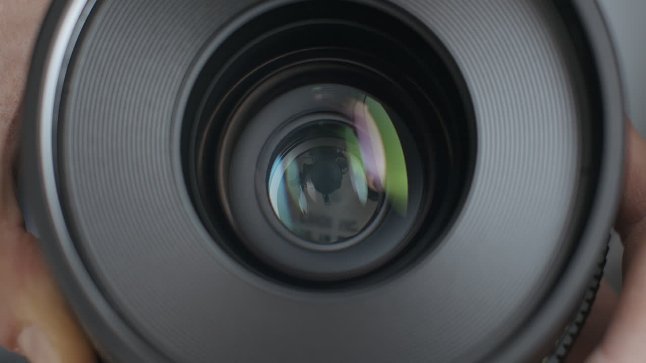 Vista frontale di una lente cinematografica in vetro e apertura del diaframma a lamelle metalliche dell'iride con meccanismo di apertura della fotocamera.