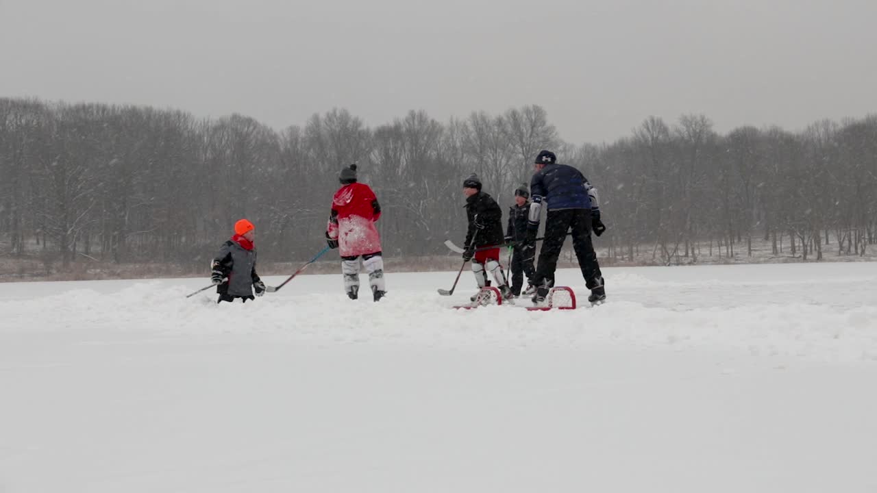Low to the ground action shot of children playing pond hockey. It's snowing and very cold but they are having a lot of fun.