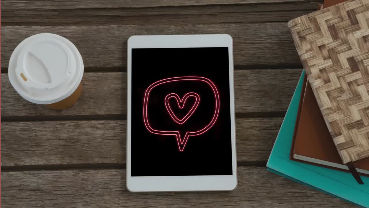 나무 책상 위에 놓인 디지털 태블릿의 화면에  ⁇ 박이는 심장 아이콘과 함께 음성 거품의 애니메이션