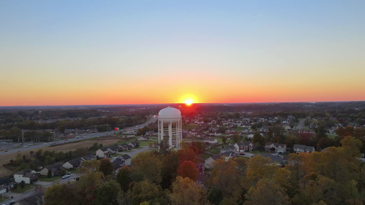 ярко-оранжевый закат над жилыми домами с водонапорной башней
