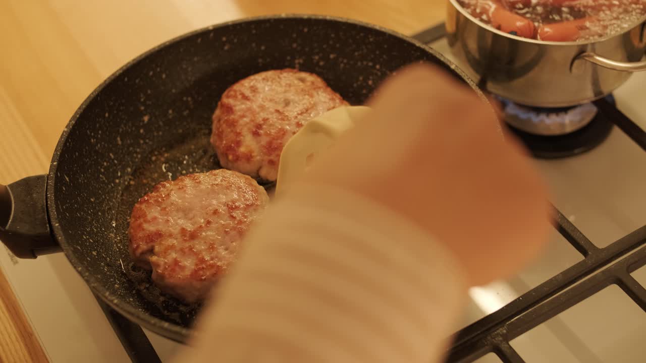 Raw meat patties frying in pan on kitchen stove
