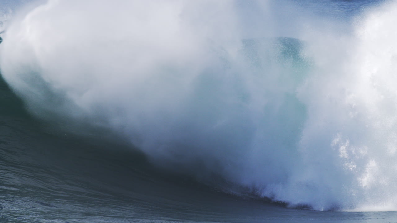 Cascading wave crashes in slow motion, mist spraying upward in dramatic backlight
