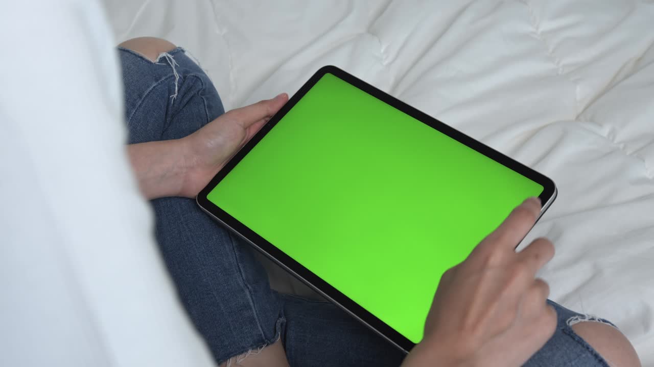 mujer sosteniendo una tableta digital con pantalla verde y dispositivo táctil navegando por internet.