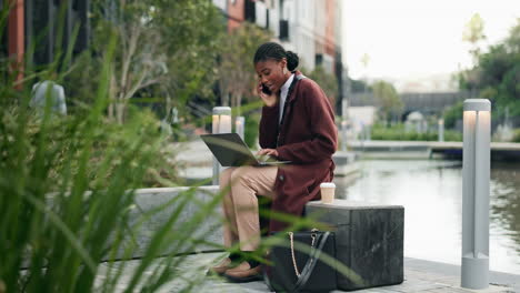 businesswoman working on a laptop and making a phone call in a city park