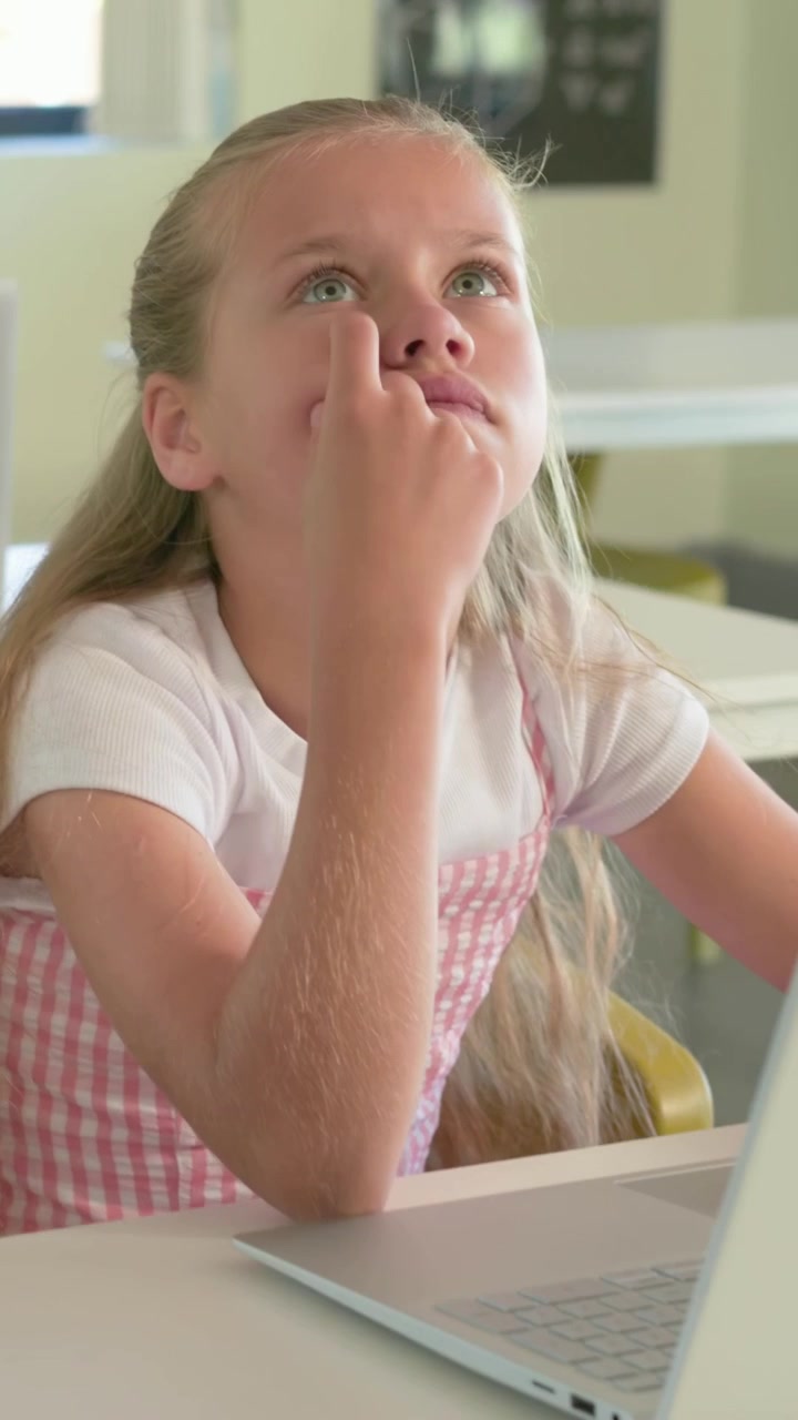 Video verticale: Laptop che emette un suono, studente che digita per i compiti, che pensa in classe, che indossa un vestito rosa.