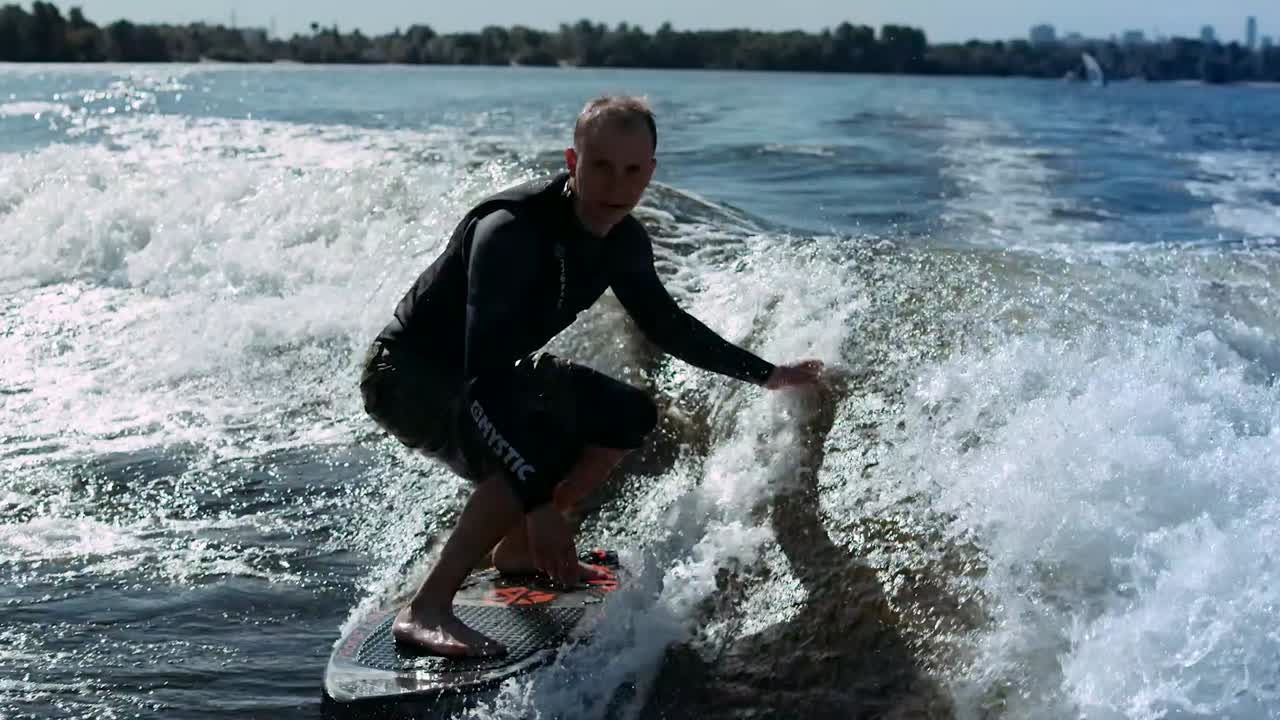hombre deportivo surfeando en wakeboard en olas en cámara lenta
