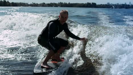 sportive man surfing on wakeboard on waves in slow motion