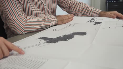 ingenieros mecánicos, diseñadores discuten problemas en planos