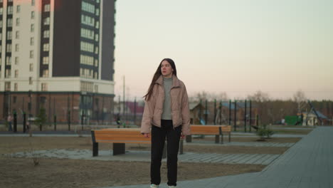 a young girl in a peach jacket and black trousers is rollerblading along a park path. the shot, taken from the front, captures her focused expression as she enjoys the activity