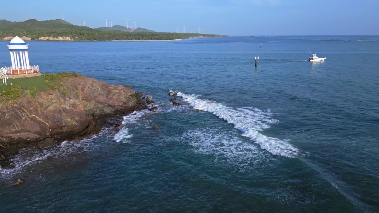 도미니카 공화국을 배경으로 에올릭 터빈이 있는 상원 의원 푸에르토 플라타 스파 리조트의 바위가 많은 곶에 있는 오래된 스타일의 정자