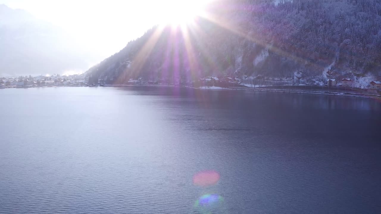 겨울에 오스트리아 언덕에 있는 호수 위를 비행하고 태양 플레어