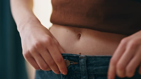 hands fastening jeans button closeup. woman checking waist weight loss progress