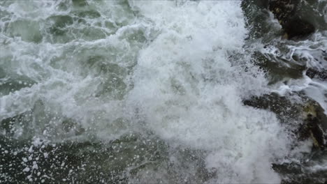 large white foam wave streaming through dark rocks