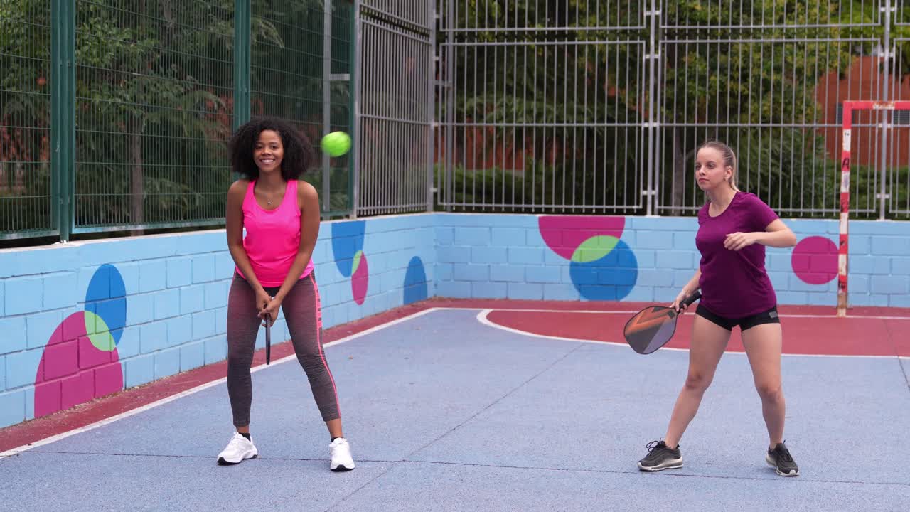 Två kvinnor som spelar pickleball på en utomhusbana