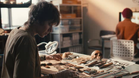 female researcher sorting archaeological artifacts on table in laboratory