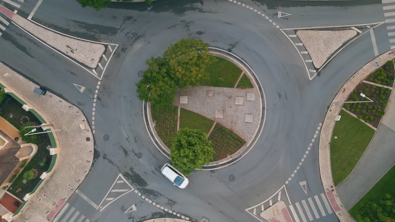 Green urban roundabout top view in small european town. Cars riding crossroad