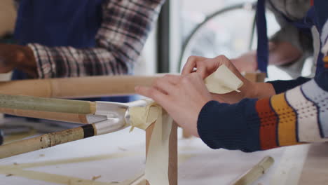 primer plano de un equipo multicultural en un taller de ensamblaje de un marco de bicicleta de bambú sostenible construido a mano