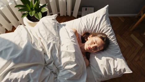 peaceful woman sleeping or waking up in a sunny bed